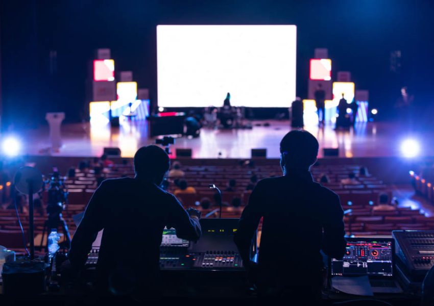 Blur image of sound engineer backstage crew team working to setting and preparing production for show events or music concert stage with blurry white screen in background.